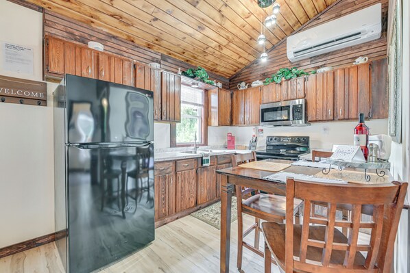 A kitchen with wooden cabinets, a black refrigerator, a microwave, and a stove. - 2 Mi to Lake Champlain: Cabin w/ River Access! (Peru)