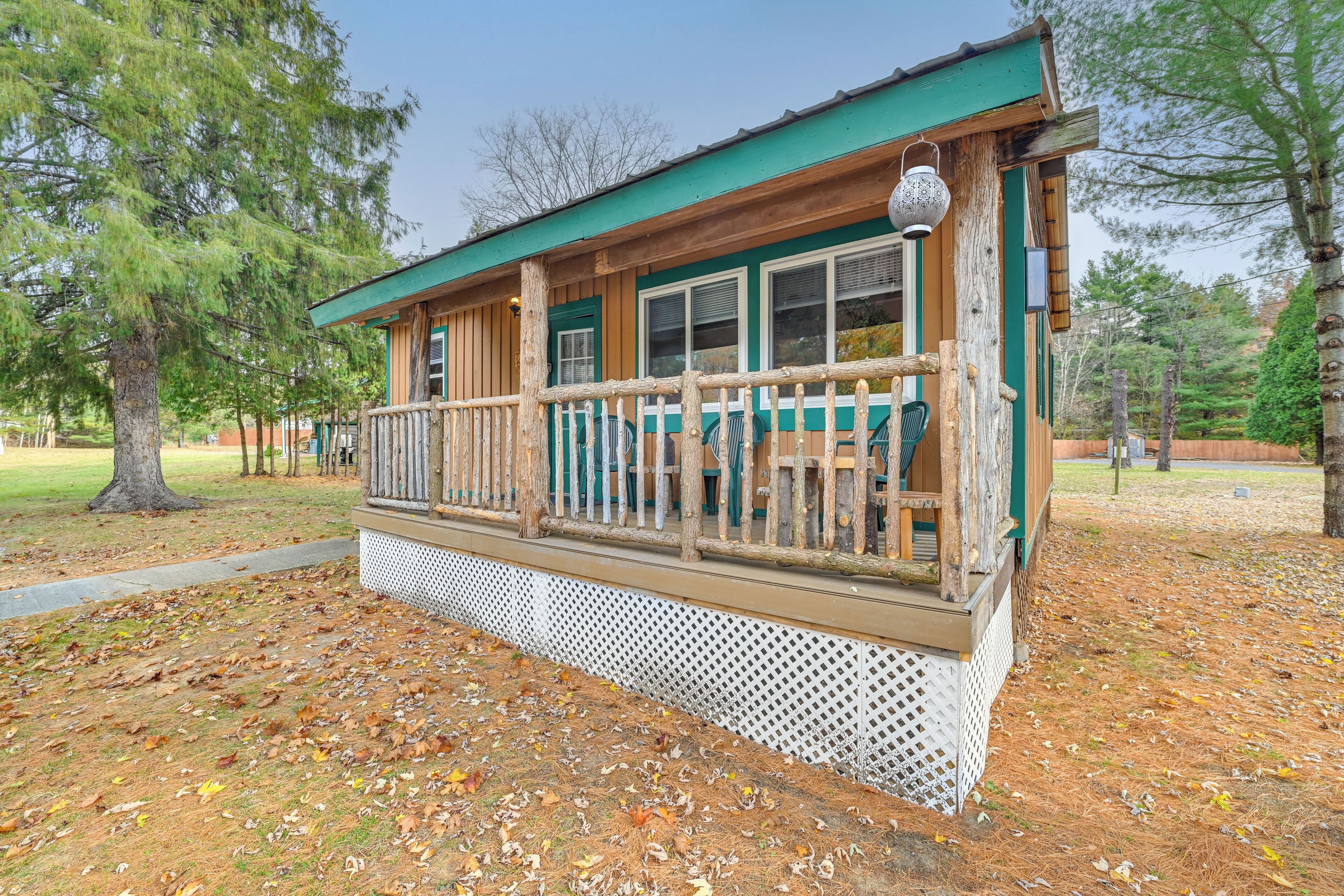 A wooden cabin with a balcony, surrounded by trees and a wooden deck.