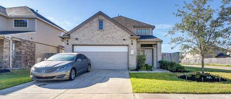 A two-story house with a garage, a driveway, and a well-maintained lawn.