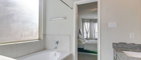 A modern bathroom with a bathtub, a shower area, and a sink.