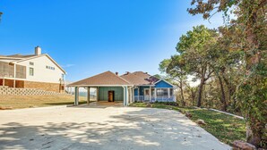 A residential street with two houses, one with a brick facade and the other with a blue exterior and a porch. - 300 Feet to Lake Texoma: Modern Home w/ Deck! (Kingston)