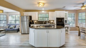 A spacious kitchen with white cabinets, a stainless steel refrigerator, and a central island. - 300 Feet to Lake Texoma: Modern Home w/ Deck! (Kingston)
