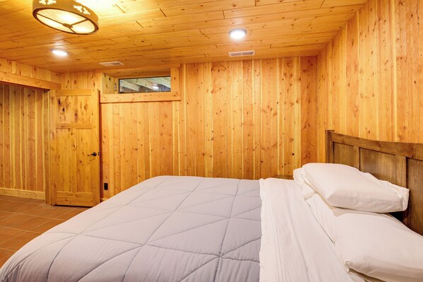 A wooden-paneled room with a bed, a door, and a window. - Nordic Style Lodge w/ Deck on 80 Acres in Arlee (Arlee)