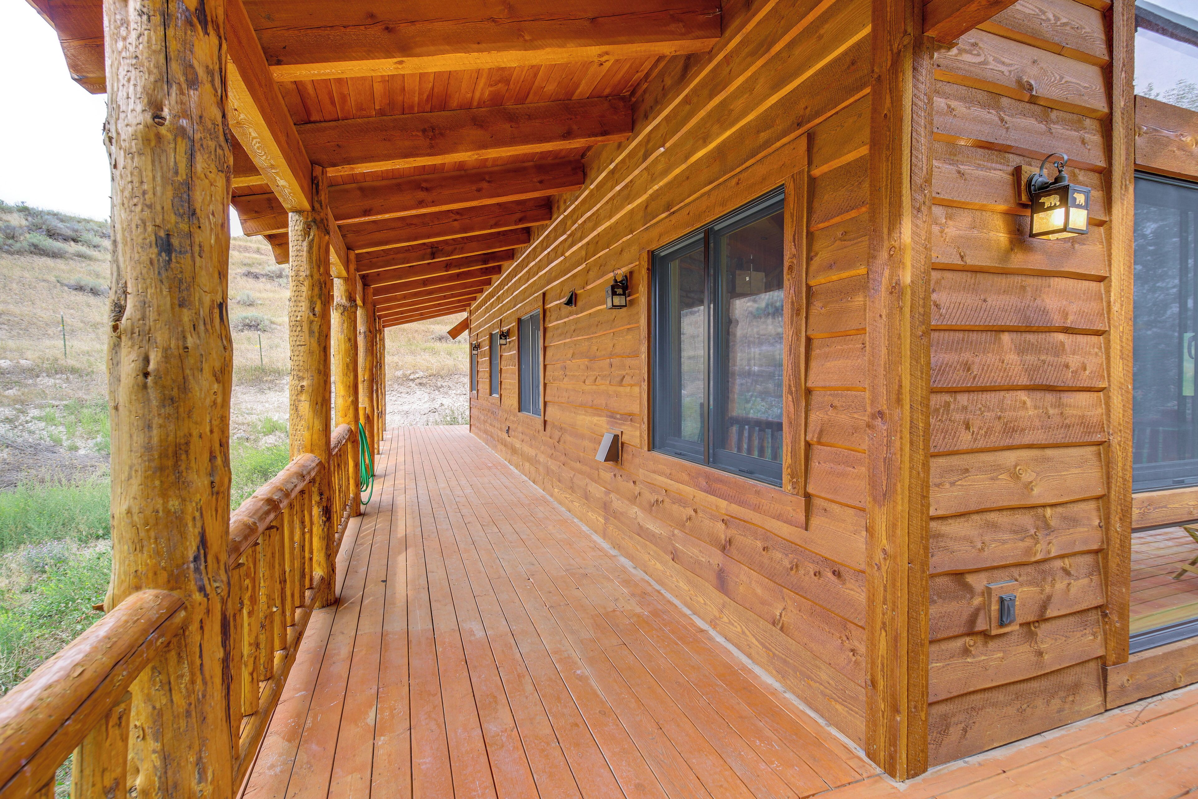 A wooden cabin with a covered porch, large windows, and a wooden deck.