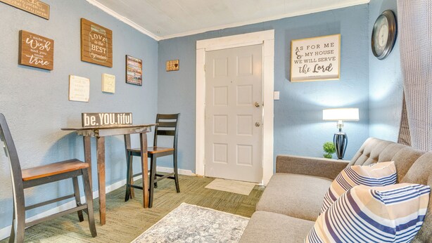 A living room with a blue wall, a wooden dining table with chairs, a sofa with striped pillows, and a door with a white frame.