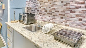A kitchen with a granite countertop, a dish rack, a toaster, and a sink.