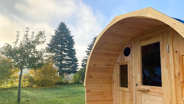 Een houten hut met een gebogen dak, een raam en een deur.