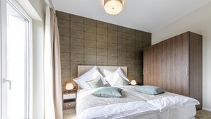 Un dormitorio moderno con una cama grande, un armario y una mesita de noche con lámpara.