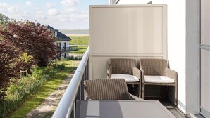 A balcony with wicker furniture and a view of the sea.