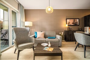 A modern living room with a sofa, armchairs, a coffee table, and a dining table.
