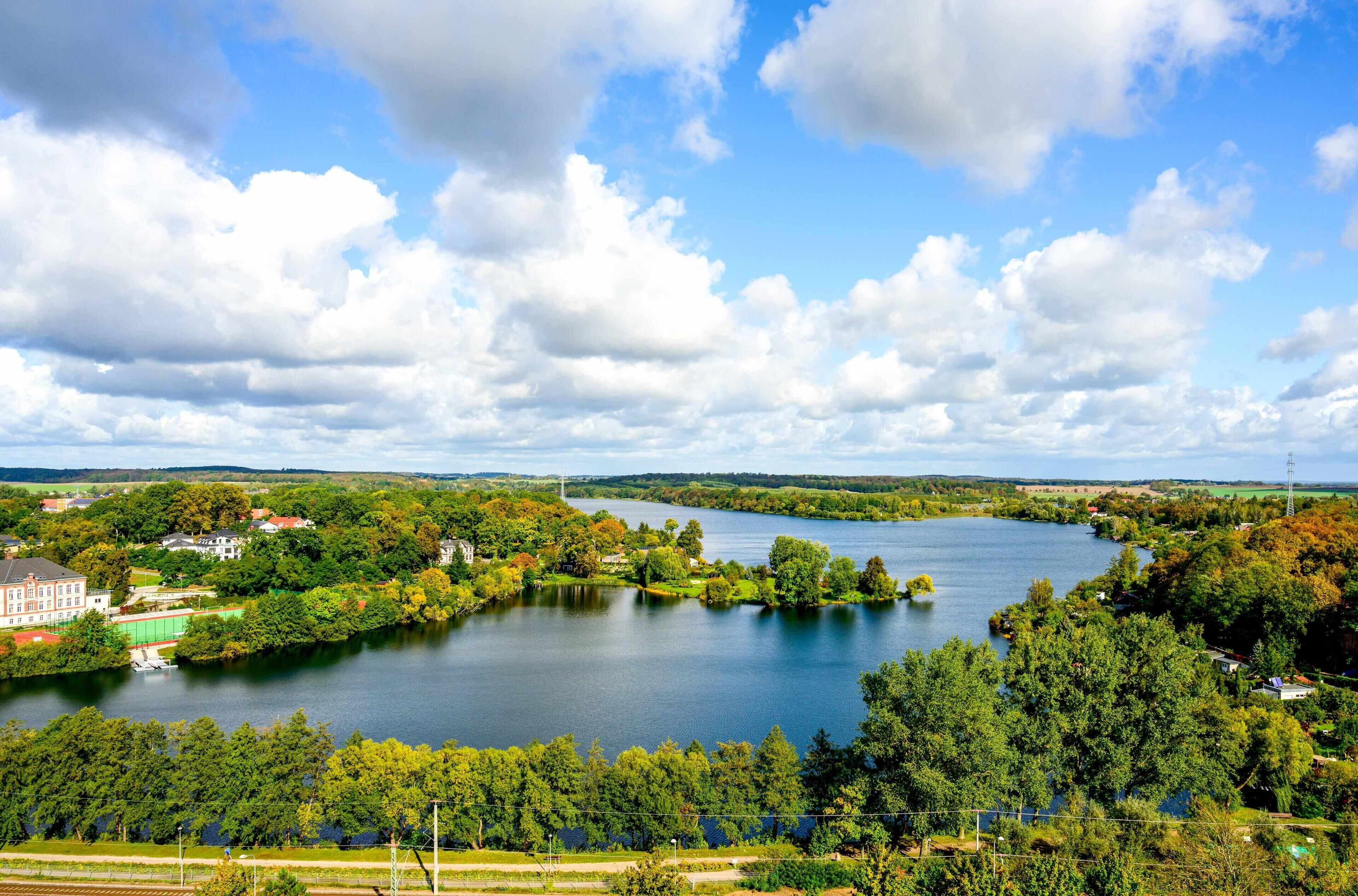 Une vue sur le lac, avec un grand bâtiment, des arbres et un ciel dégagé.