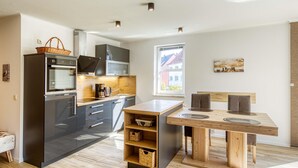 Una cocina moderna con horno empotrado, una isla de madera con fregadero y una mesa de comedor con sillas.