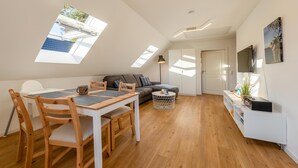 Un appartement moderne de style «loft», comprenant un coin repas, un canapé, un téléviseur et une petite table d’appoint.