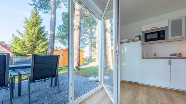 Une cuisine moderne dotée d’une porte-fenêtre coulissante donnant sur un patio aménagé avec des sièges d’extérieur.