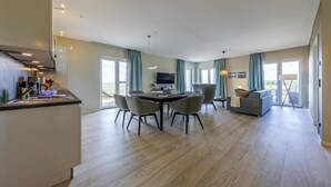 A modern living room with a dining area, a kitchen, and a sofa. - 5-star vacation apartment Boddenkieker between the Baltic Sea and the Bodden (Wustrow)