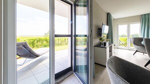 A modern room with a balcony, a sofa, a TV, and a table with a vase. - 5-star vacation apartment Boddenkieker between the Baltic Sea and the Bodden (Wustrow)