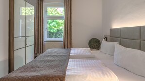 Un dormitorio con dos camas, un armario y una ventana con cortinas.