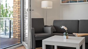 Een moderne woonkamer met een grijze bank, een witte salontafel en een vloerlamp.