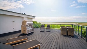 Eine Terrasse mit Liegestühlen, einem Grill und Blick auf einen Golfplatz.