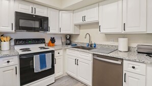 A modern kitchen with white cabinets, a stainless steel microwave, a stove, a sink, and a dishwasher. - Hoff Gardens 38 - 1BR/1BA - Downtown Lubbock (Lubbock)