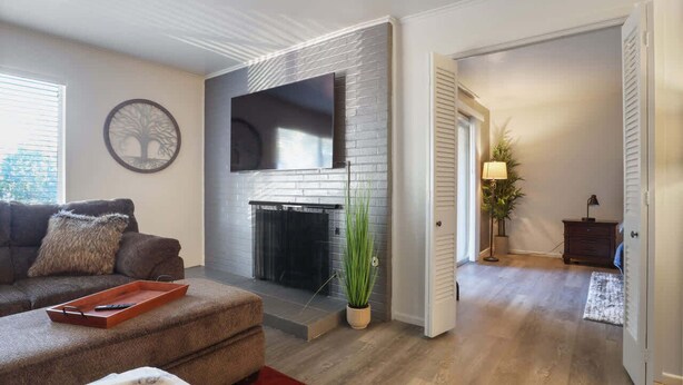 A living room with a fireplace, a sofa, a coffee table, and a TV mounted on the wall. - Hoff Gardens 38 - 1BR/1BA - Downtown Lubbock (Lubbock)