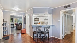 A modern kitchen with a bar area, wooden flooring, and a view into the living room. - Hoff Gardens 38 - 1BR/1BA - Downtown Lubbock (Lubbock)