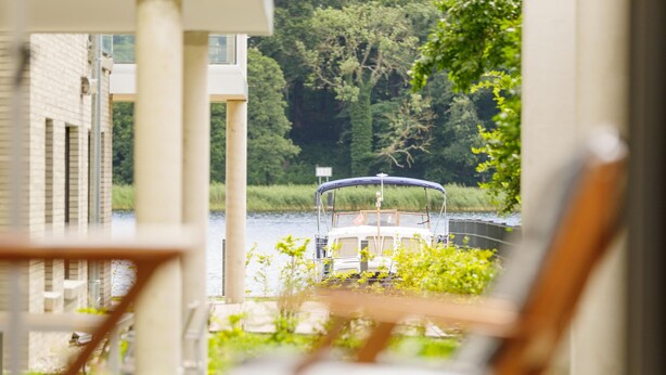 A boat docked at a pier with a view of a building and greenery in the background. - "Nordlicht" Vacation Rental in the Island Town of Malchow (Malchow)