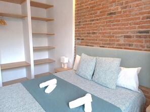 Une chambre à coucher avec un lit, un mur en briques et des étagères en bois.