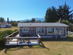 Ein eingeschossiges Haus mit Terrasse, Naturstein-Fassade und großen Fenstern.
