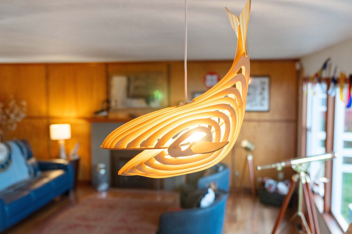 A modern living room with a hanging light fixture, a blue sofa, and a wooden reception desk.