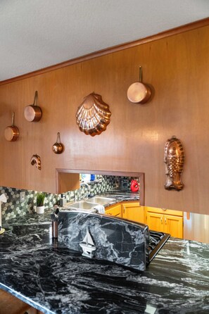 A kitchen with a black marble countertop, wooden cabinets, and a backsplash with hexagonal tiles.