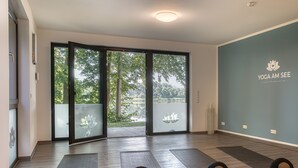 A yoga studio with large sliding glass doors, wooden flooring, and yoga mats.