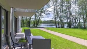 A covered outdoor seating area with a view of a lake and trees.