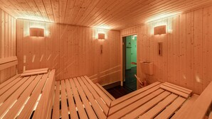 A wooden sauna room with benches and wall-mounted lights.