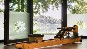 A rowing machine in a room with large windows overlooking a lake. - 5 star vacation apartment "Waldameise" with terrace in Krakower am See (Krakow am See)