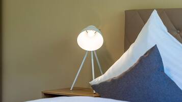 A neatly made bed with white bedding, a bedside lamp with a white shade, and a brown headboard.
