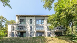 A modern two-story building with balconies, large windows, and a grassy area in front. - Vacation apartment "Silberreiher" with balcony in Krakow am See (Krakow am See)