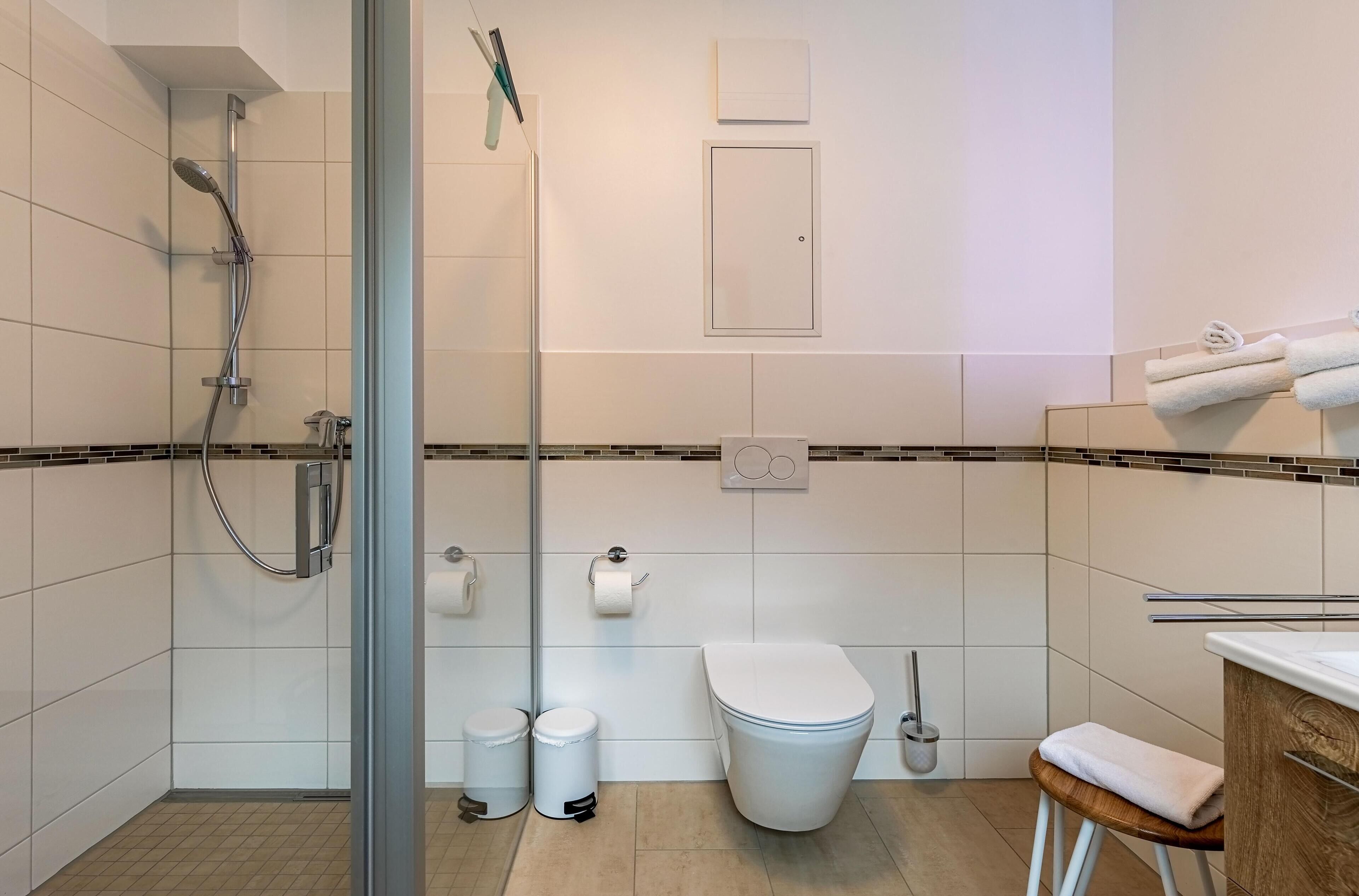 Ein modernes Badezimmer mit einer Duschkabine, einer Toilette und einem Waschbecken mit Handtuchhalter.