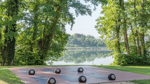 Un espacio pavimentado con pelotas de ejercicio y un lago al fondo.