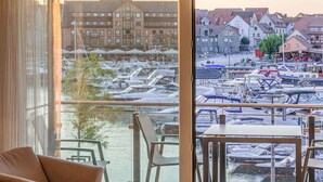 Näkymä parvekkeelta, jolta avautuu näkymä venesatamaan, jossa on veneitä, ravintola ja perinteisiä rakennuksia.