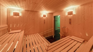 Un sauna en bois, doté de bancs et de lampes fixées au mur.