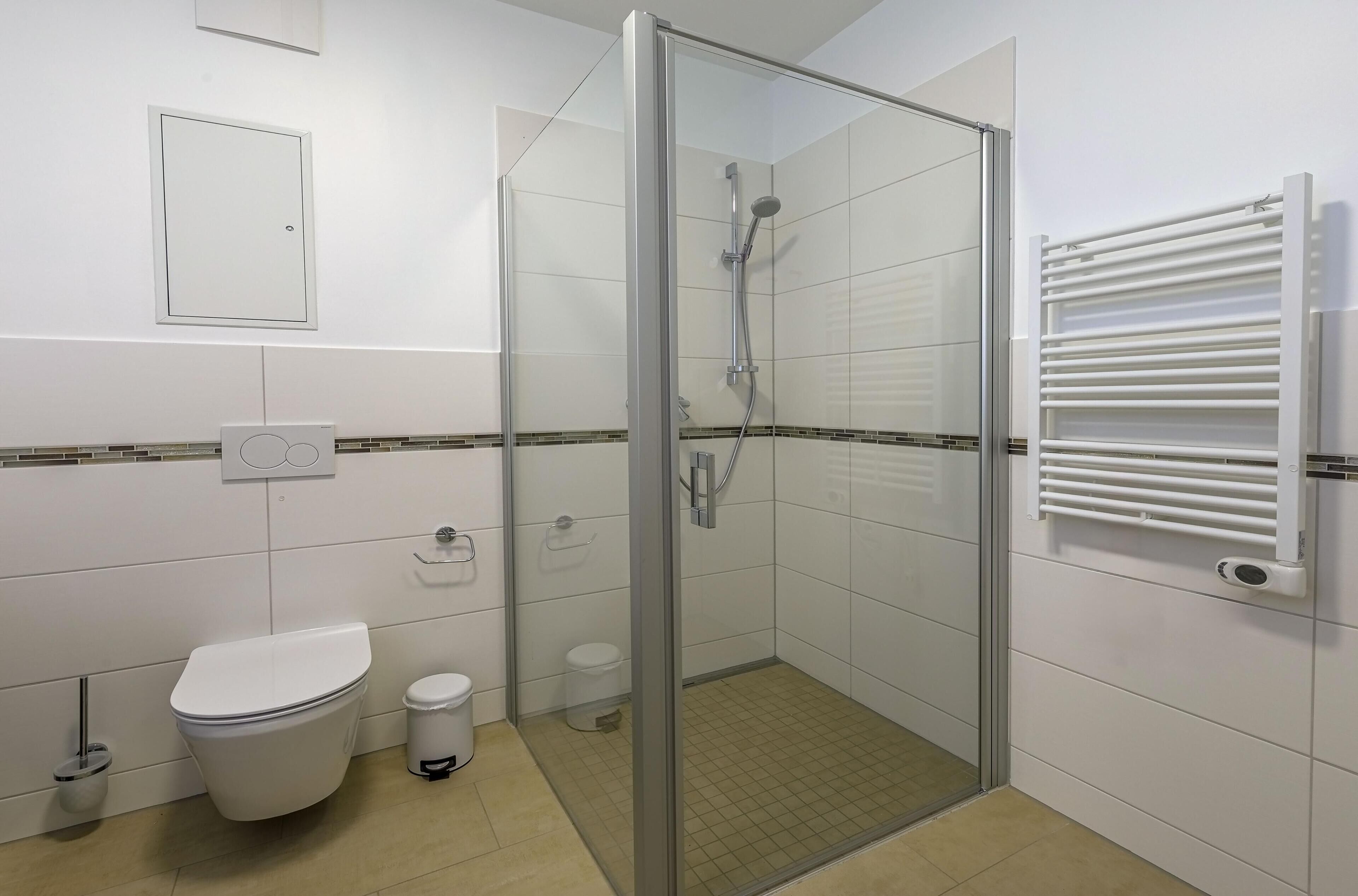 Une salle de bain moderne avec une douche à parois de verre, des toilettes et un porte-serviettes.