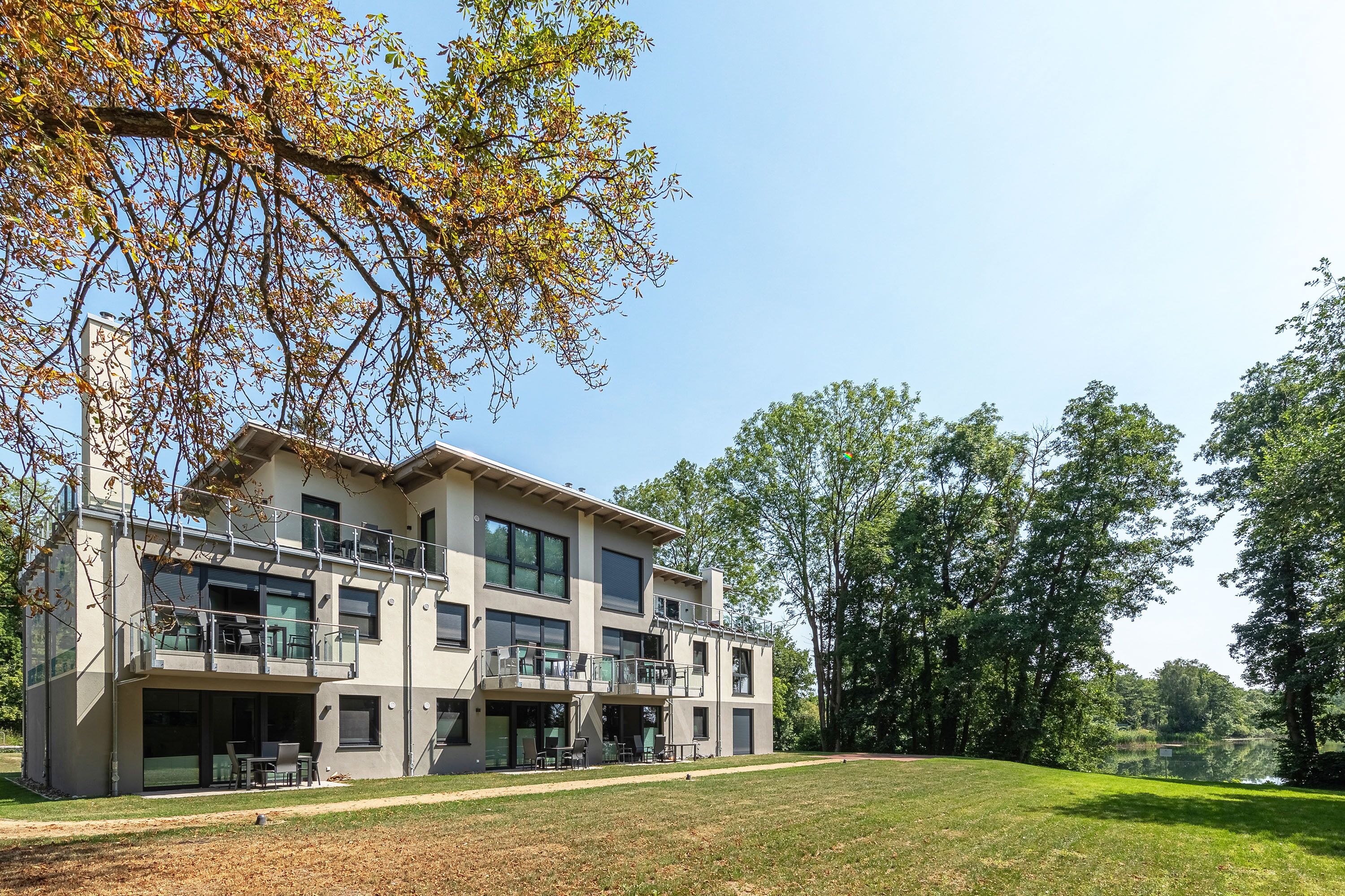 Ein modernes, zweistöckiges Gebäude mit Balkon, großen Fenstern und einem Rasen.