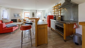 Eine moderne Küche mit Kochinsel, Barhocker, einem roten Sofa und einem Essbereich mit Blick auf die Stadt.