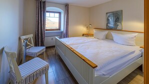 Ein Schlafzimmer mit einem großen Bett, einem Sessel, einem Fenster und einem Gemälde an der Wand.