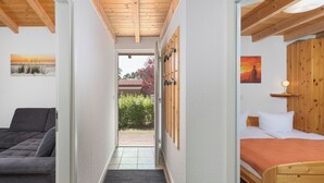 A narrow hallway leading to a bedroom with a bed, a sofa, and wooden ceiling beams. - "Sonnenschein" Vacation Home on Lake Jabelschen (Jabel)