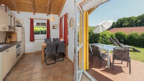 A kitchen with a dining area, a table with chairs, and a view of the garden through a glass door. - "Sonnenschein" Vacation Home on Lake Jabelschen (Jabel)
