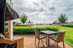 Eine Terrasse im Freien mit Korbmöbeln, einem Tisch und Stühlen.