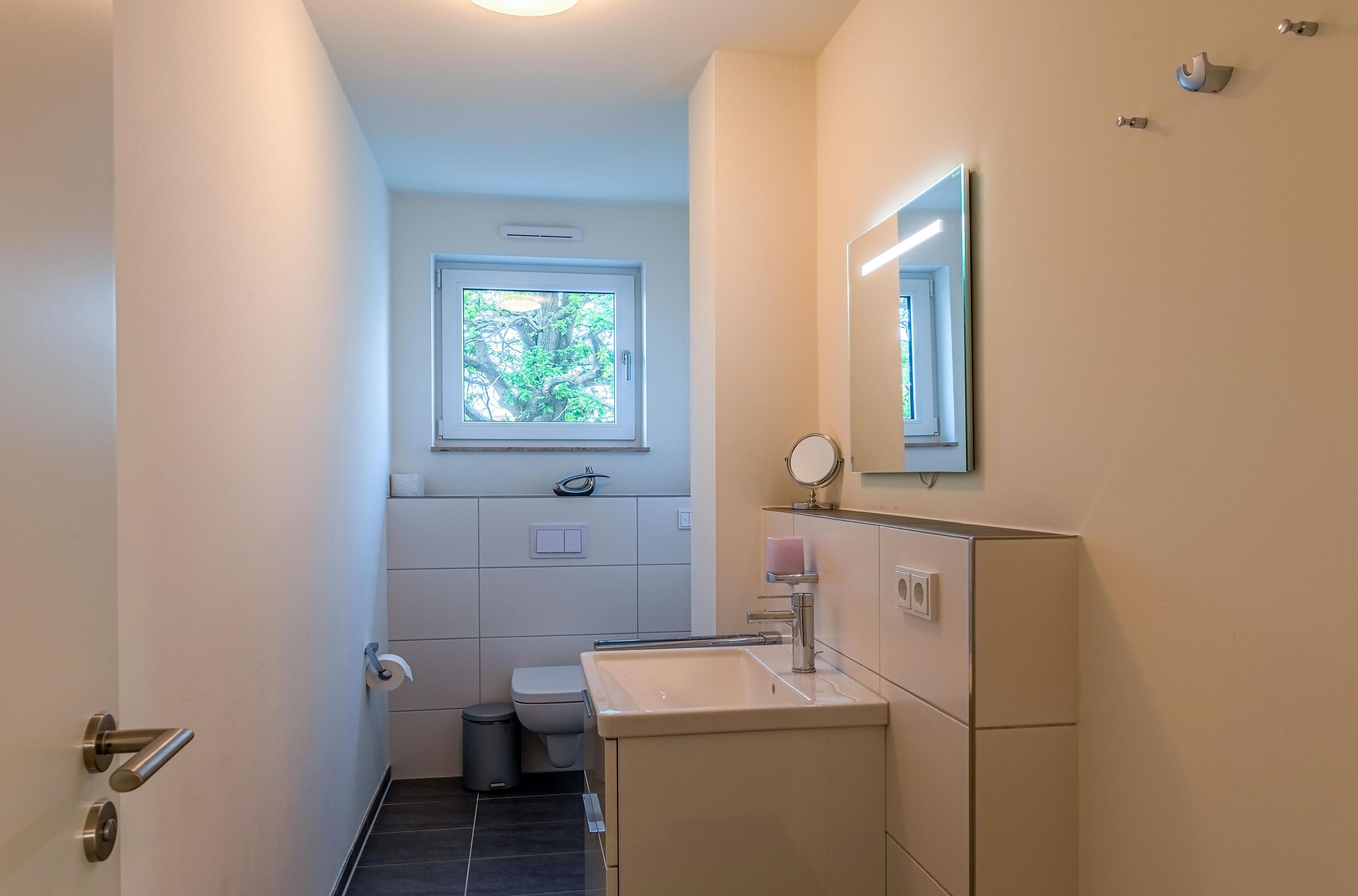 A compact bathroom with a toilet, sink, and window.