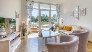 A modern living room with a sofa, armchairs, a coffee table, and a TV.